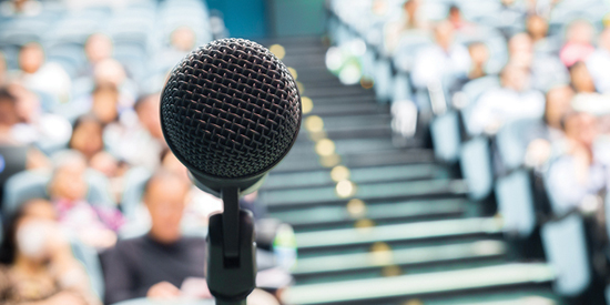 Microphone in front of out of focus audience sitting down