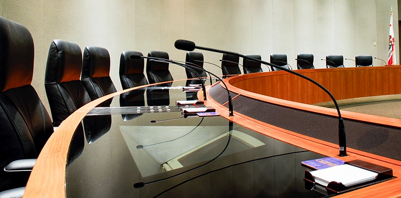 Circular conference room with microphones and notepads in front of chairs 
